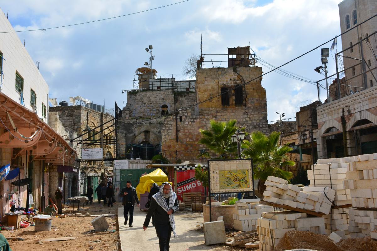 Chantier de restauration dans la vieille ville d'Hébron, bâtiments en ruine surplombés par des postes militaires israéliens
